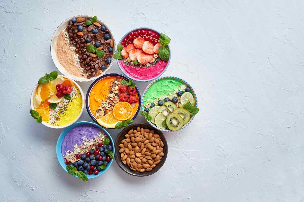 Platos con alimentos multicolor sobre una mesa blanca