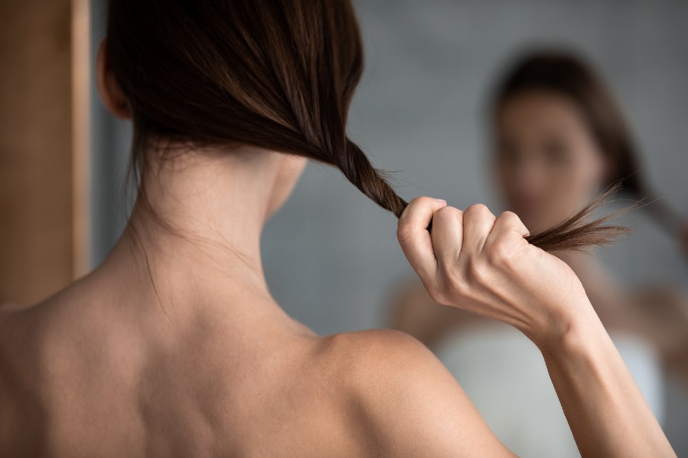 Mujer se toca el pelo frente al espejo