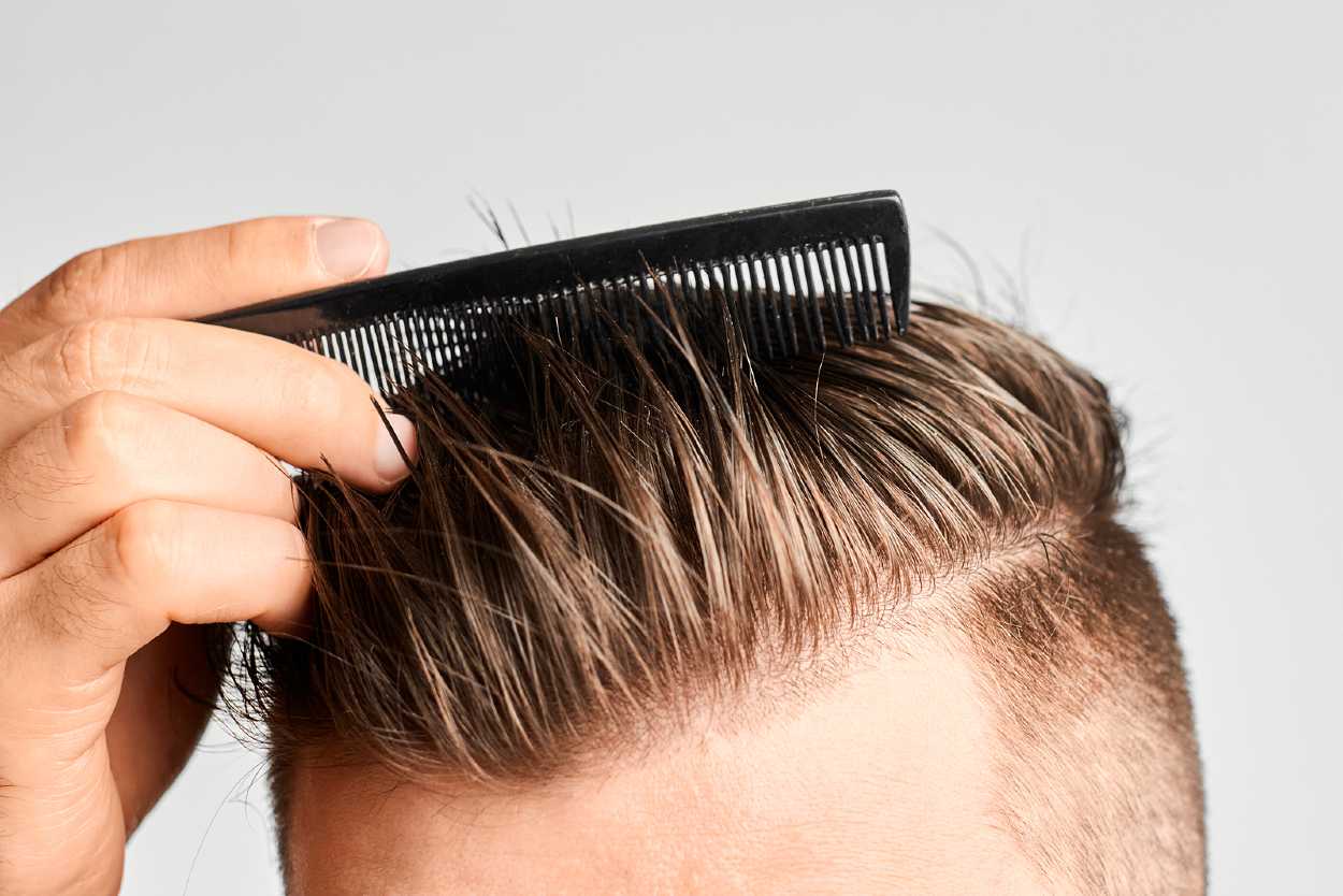 Hombre peinándose el cabello hacia el lado con un peine fino