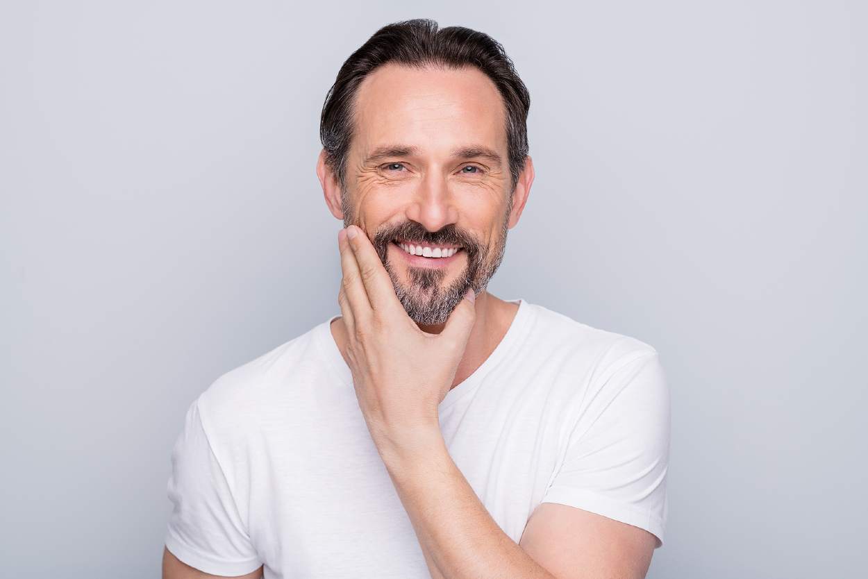 Hombre de mediana edad tocándose la barba y sonriendo