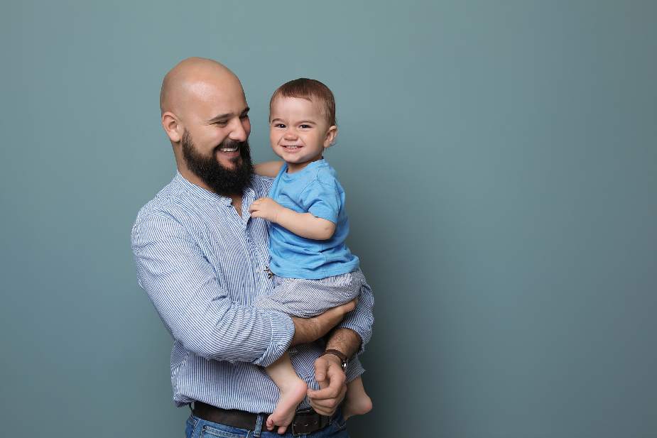 Hombre calvo sosteniendo a su bebé en brazos. La calvicie genética puede ser hereditaria