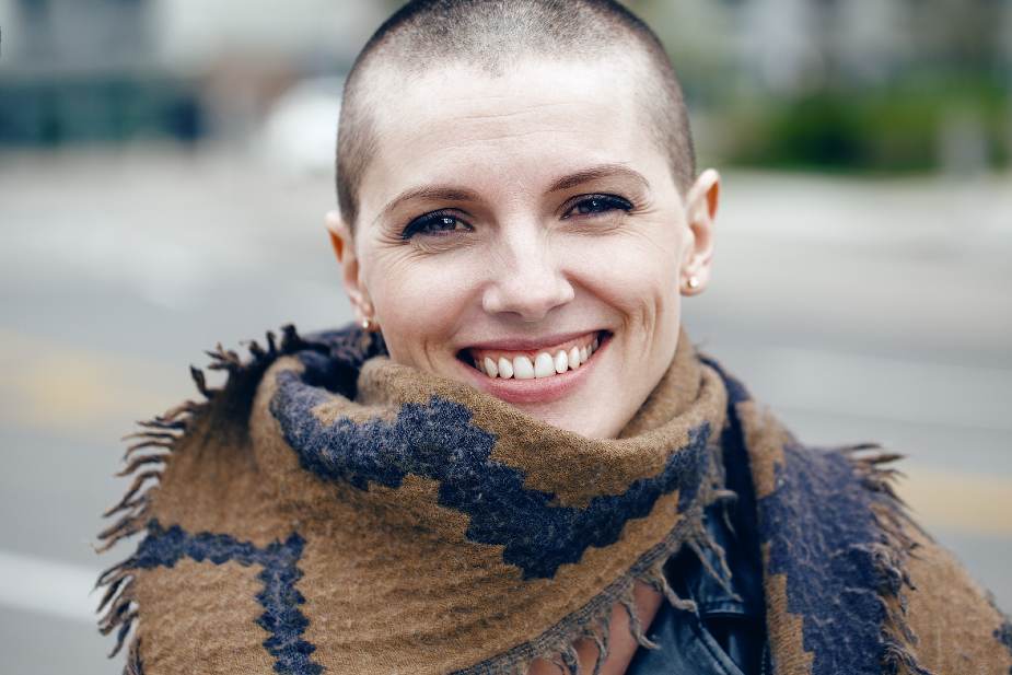 Mujer sonriente con cabeza rapada y bufanda