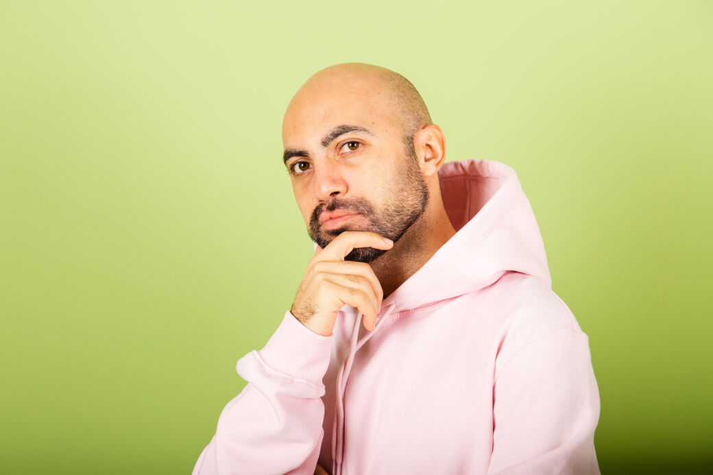 Joven caucásico calvo con sudadera rosa aislado sobre fondo verde preocupado por una pregunta, prótesis capilar o injerto capilar?