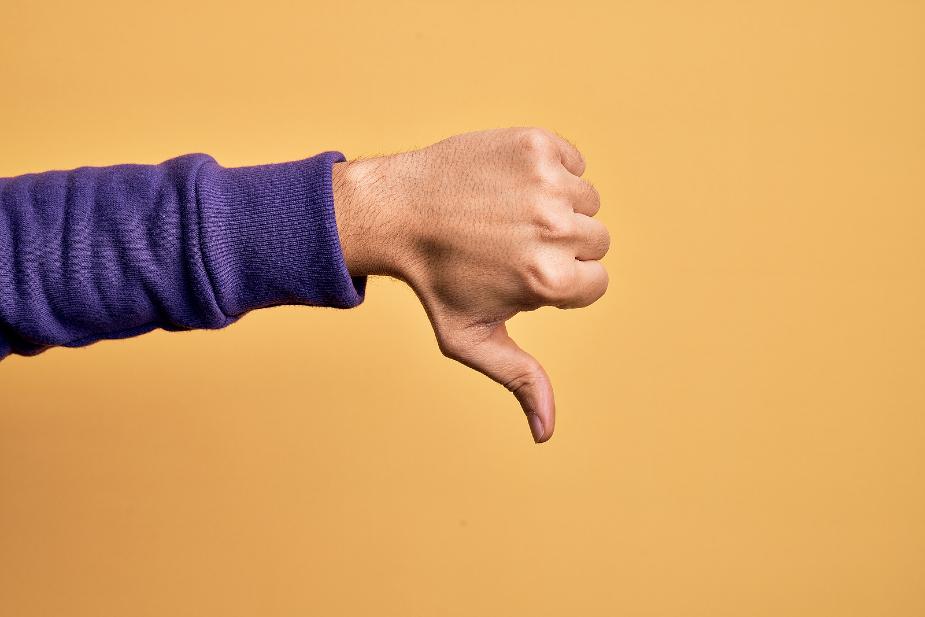 Mano apuntando hacia abajo simbolizando los efectos secundarios del injerto capilar