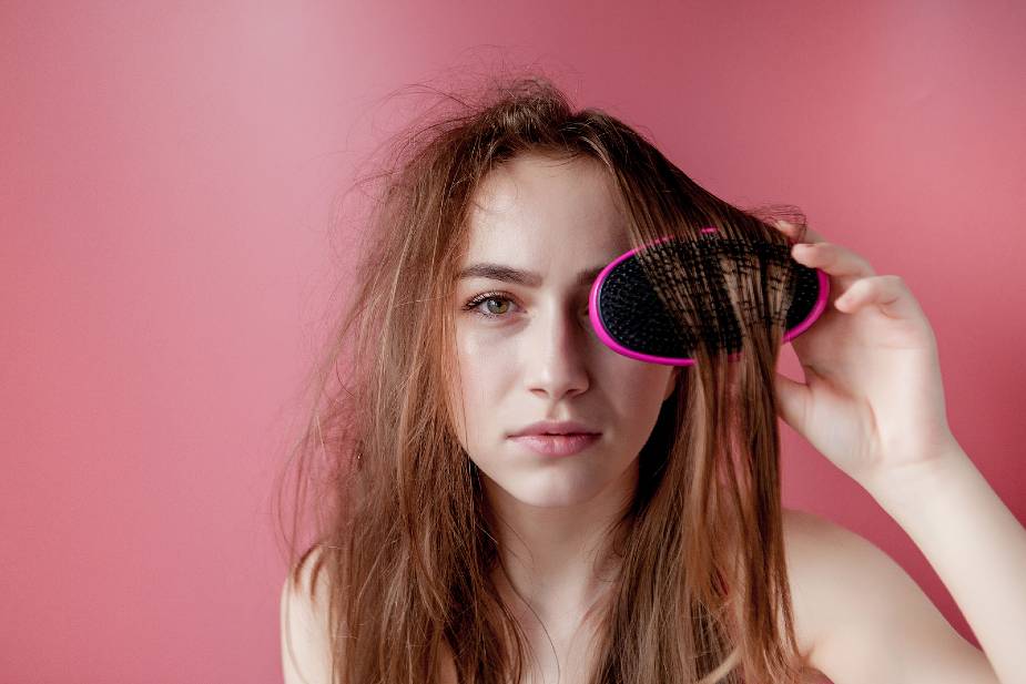 Mujer con pelo graso intentando desenredar el pelo