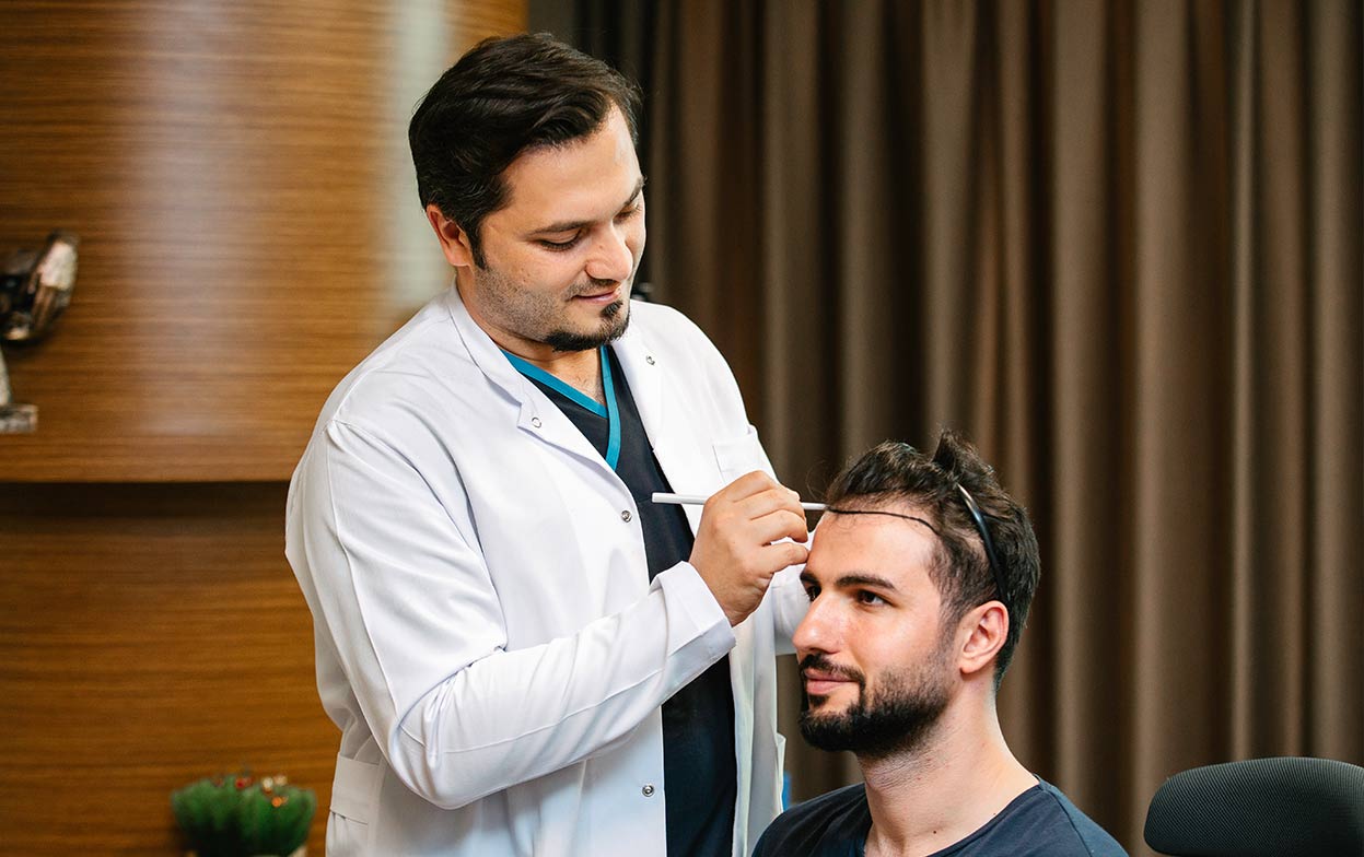 El Dr. Balwi disenando la línea frontal del cabello durante la preparación del trasplante capilar